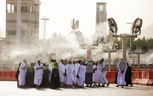 A crowd of people standing below a cooling station in Saudi Arabia, in preparation for the upcoming Hajj season