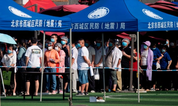 People who live near or have visited the Xinfadi food market wear masks while queueing for testing at the Guang’an sports centre in Beijing