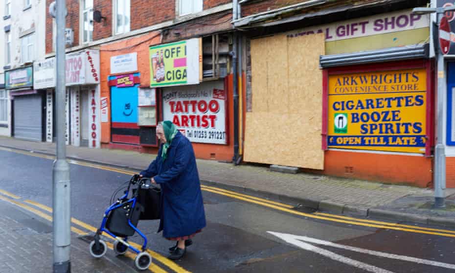 A woman pushes her shopping bag past closed shops in The Fylde, Lancashire