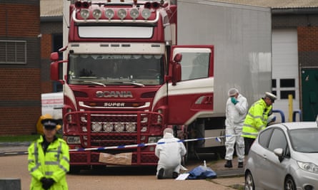 People in hi-vis jackets and white paper coveralls work around a red and white lorry