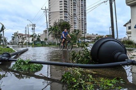 A man cycles through water past a downed street lamp in aftermath of Hurricane Ian in Fort Myers.