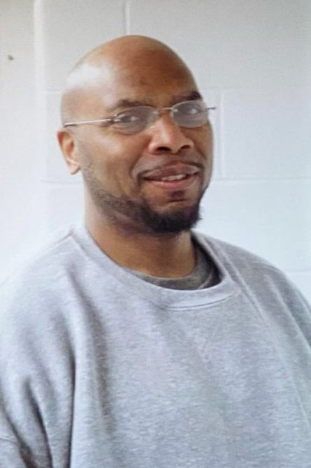 A man with a bald head and glasses in a gray sweatshirt.
