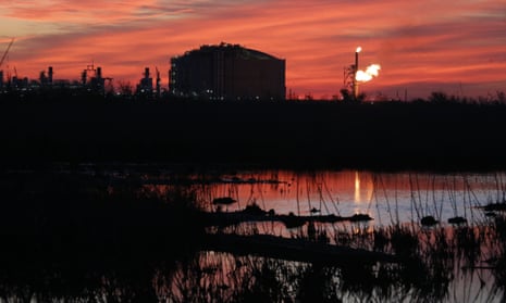 A flare burns at an LNG terminal during a sunset
