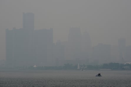 buildings covered in smoke next to a body of water