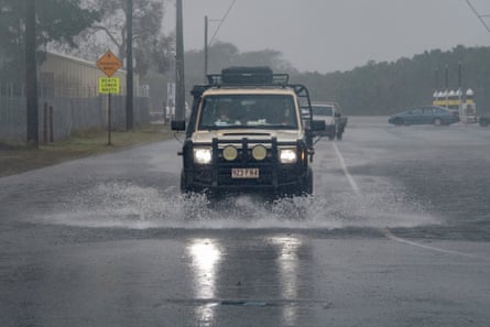 Cars drive through floodwater as Cyclone Jasper approaches landfall in Cairns.