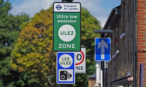 Street signs including an arrow and signs reading "Ultra low emission Ulez zone" and "Lez Ulez" with a camera motif