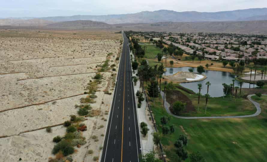 A lush green golf course next to dry desert landscape in Palm Desert, California.
