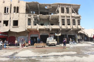 Shop owners outside a damaged building in new Mosul.