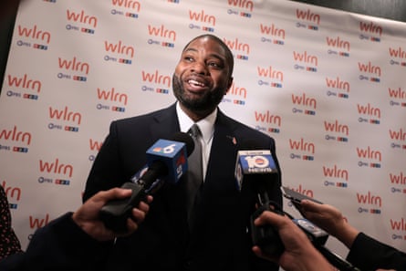People hold microphones in the direction of a man speaking