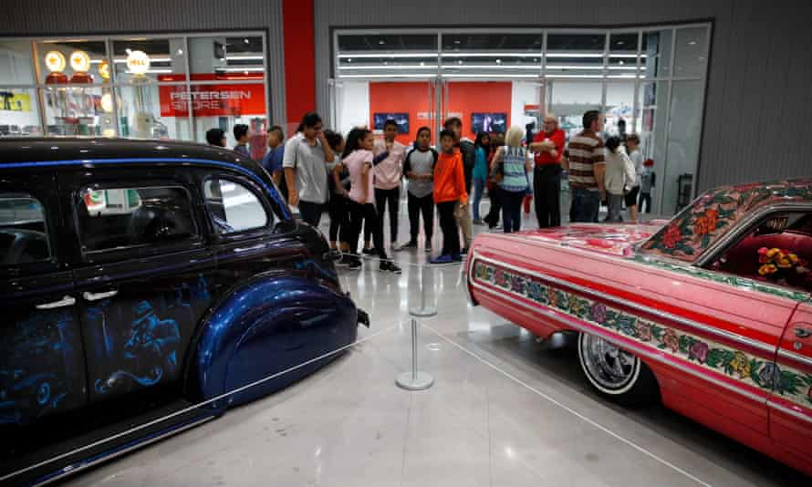 Visitors stand in front of 1939 Chevrolet Master Deluxe, named Gangster Squad '39, left, and Jesse Valadez's Gypsy Rose, a customized 1964 Chevrolet Impala, during an exhibition titled The High Art of Riding Low at the Petersen Automotive Museum in Los Angeles in 2017.