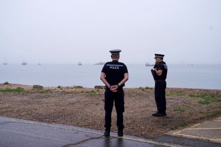 Two policemen standing with the sea in the distance