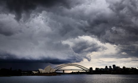 A view across the harbour of storm clouds forming above the Sydney Opera House and the harbour bridge