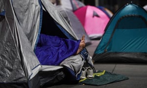 A pair of feet stick out of a tent used by a homeless person