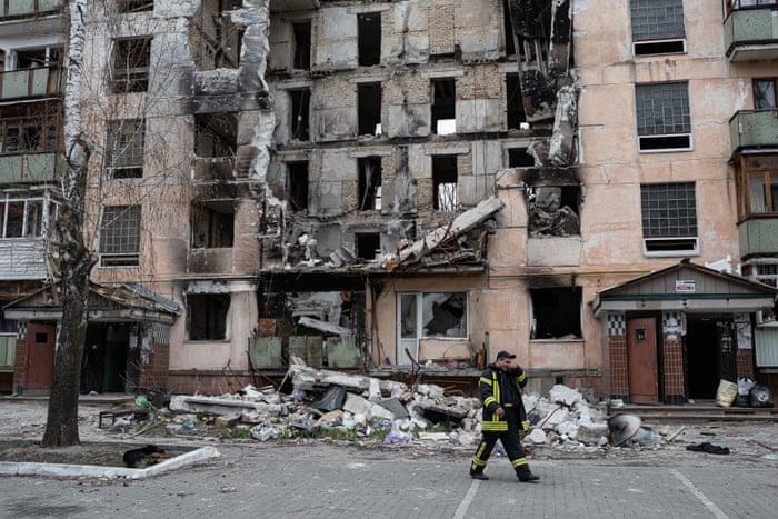 A rescue worker walks past a heavily damaged apartment building in Hostomel, Ukraine.