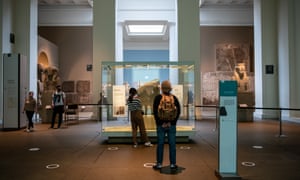 Visitors wearing face masks look at the Rosetta Stone next to social distancing markers on the floor at the British Museum on August 27, 2020 in London, England. The British Museum has reopened to the public after being closed for 163 days due to Covid-19 restrictions and lockdown. Many other museums have already reopened in the United Kingdom with safety precautions in place to help prevent the spread of Covid-19. (Photo by Chris J Ratcliffe/Getty Images)