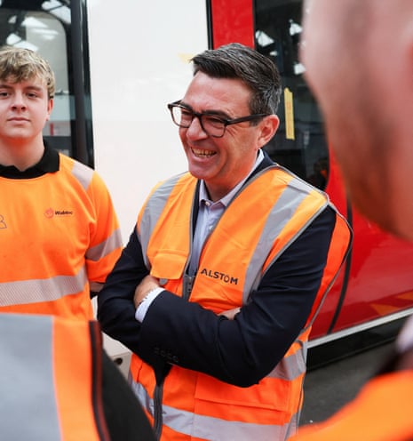 Andy Burnham smiles in a high vis vest while meeting transport workers
