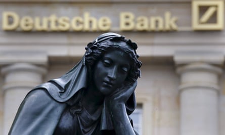 A statue next to the logo of Germany’s Deutsche Bank in Frankfurt, Germany