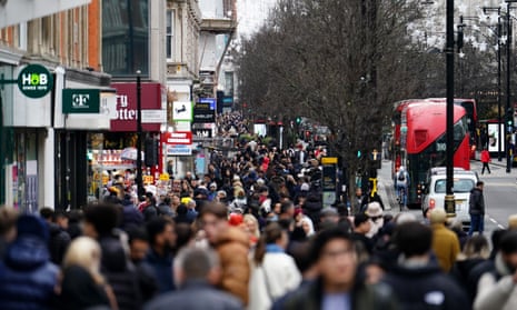 Busy high street filled with people, and a London bus on the road