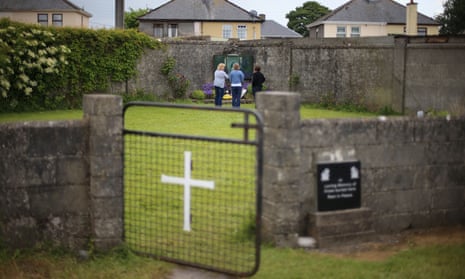 People stand at the site of a mass grave for children who died in the Tuam mother and baby home, County Galway
