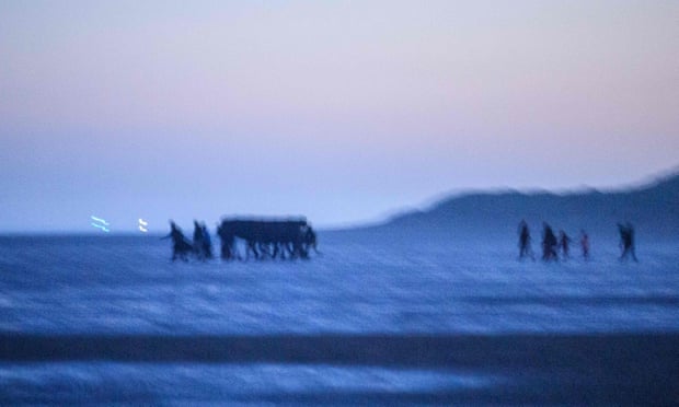 Migrants carry a boat on the beach at Gravelines, near Dunkirk