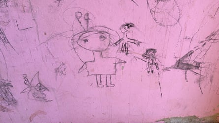 Children’s drawings on a wall of people, one firing a pistol