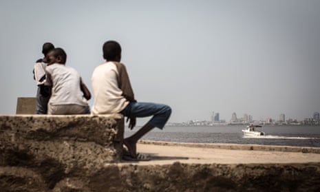 A group of children sit on the shores of the Congo river in Brazzaville looking across to Kinshasa