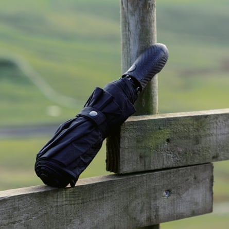 Folded-up compact umbrella on top of a fence and leaning against a fence post