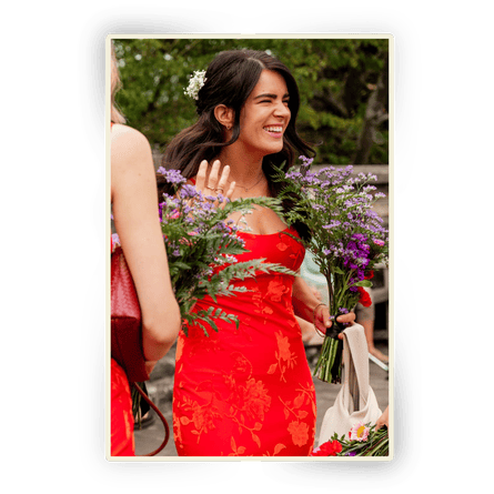 Davis in bright red bridesmaid’s dress holding a bunch of purple flowers
