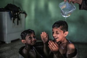 A Palestinian mother washes her sons in their house during hot weather in a slum on the outskirts of Khan Younis refugee camp, Gaza Strip, Lebanon