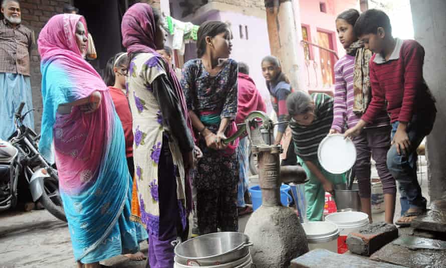 People collect water from a hand pump in the Azadpur area of north Delhi