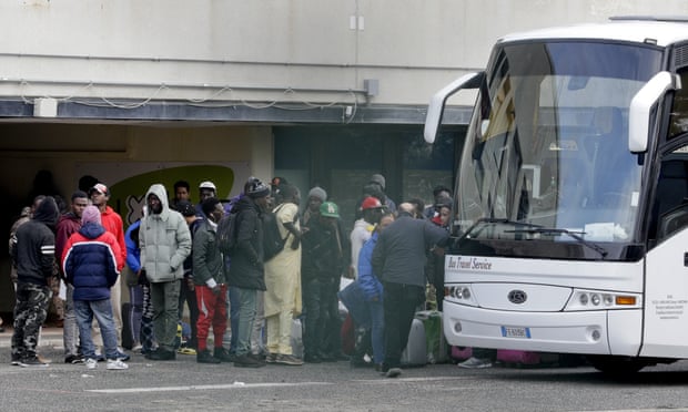 Migrants wait to board a bus to leave the Castelnuovo di Porto centre