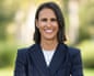 Megan Rose smiles outdoors in a pinstripe blazer, arms crossed