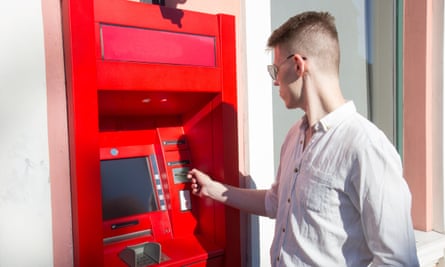 young man student withdrawing money from a bank cash point