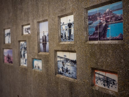A concrete wall with tiles embedded that show seaside scenes from the mid-20th century