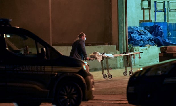A man wheels a gurney into a warehouse in the Port of Calais, France, where it is believed the bodies of migrants are being transported after recovery from a boat which capsized off the French coast