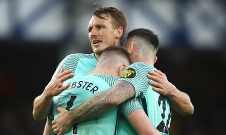 The 6ft 7in Dan Burn is embraced by Brighton teammates at Everton this month