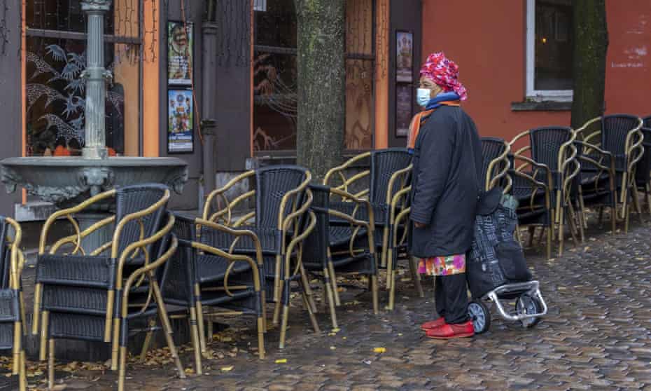 A woman wears a face mask as she passes by an empty terrace in the Marrolles quarter in Brussels, Belgium.