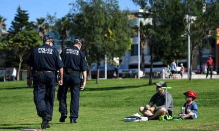 uniformed police walk by a father and small child in a park