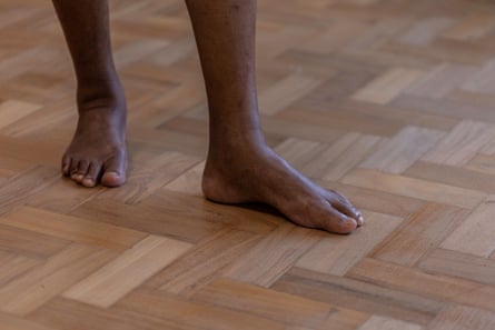 A pair of feet stand on a wooden floor