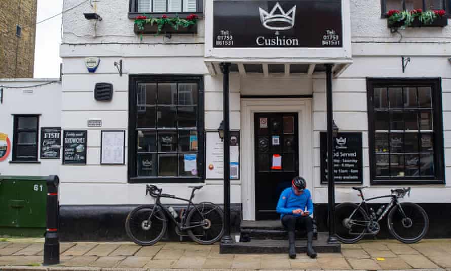A man sits outside a closed pub in Eton, Berkshire