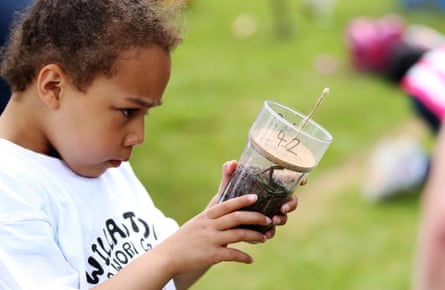 Little girl holding contianer filled with worms.