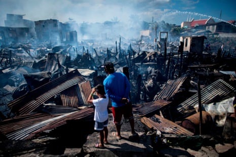Residents look at destroyed houses after a fire engulfed a slum area in Navotas, Philippines