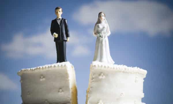 Un gâteau de mariage fendu avec la figurine d'un marié sur une tranche et d'une mariée sur l'autre