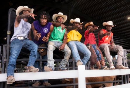 A group of men and young boy in cowboy hats point towards the distance