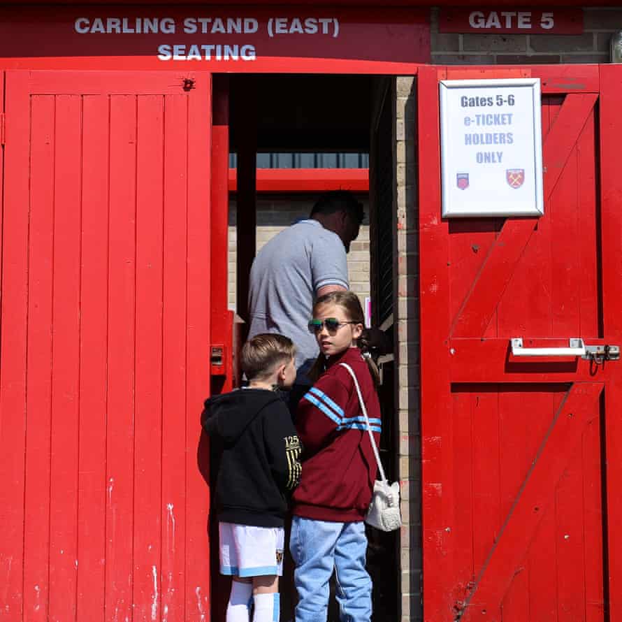 A young West Ham fan looks over her shoulder as she walks through the turnstiles with her father and brother.