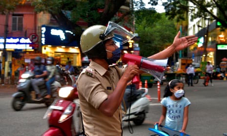 A police officer uses a loudspeaker to disperse people gathered in Bangalore as residents prepare for a week-long lockdown.