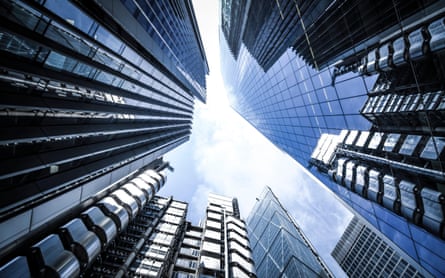 A picture, looking up, of the sharp edges of skyscrapers with mirrored windows which appear to converge at the top in front of a slightly cloudy sky
