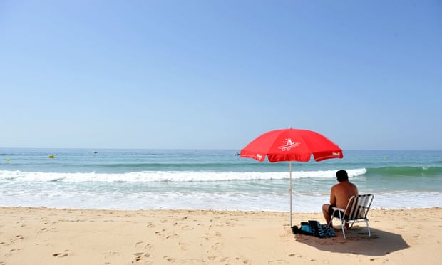 man sitting under an umbrella on a portuguese beach