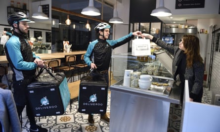 Deliveroo couriers picking up meals for delivery from a restaurant.