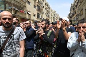 A group of men march down a street in Damascus, Syria, protesting against those killed in recent clashes. Some are clapping